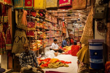 JAIPUR, INDIA 13 AĞUSTOS 2019: Geleneksel sari ve kumaş satan tüccarlar, Jaipur, Jaipur, Hindistan 'ın geleneksel doğu el sanatları merkezidir