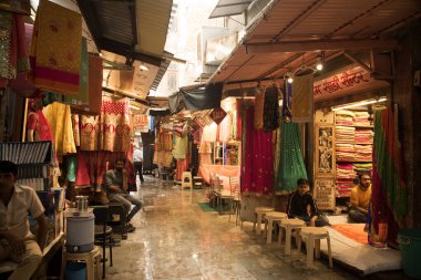 JAIPUR, INDIA 13 AĞUSTOS 2019: Geleneksel sari ve kumaş satan tüccarlar, Jaipur, Jaipur, Hindistan 'ın geleneksel doğu el sanatları merkezidir