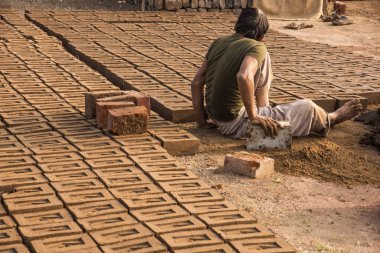 AURANGABAD, MAHARASHTRA, INDIA, 26 Kasım 2019: Kalıplardan ıslak kil tuğlalar yapan Hintli işçiler açık havada güneş ışığında kurutmak için elle kil tuğlalar yapıyorlar.