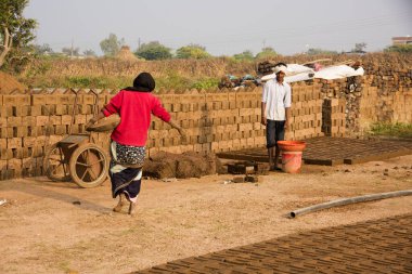 AURANGABAD, MAHARASHTRA, INDIA, 26 Kasım 2019: Kalıplardan ıslak kil tuğlalar yapan Hintli işçiler açık havada güneş ışığında kurutmak için elle kil tuğlalar yapıyorlar.