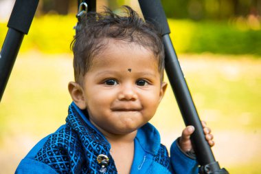 Şirin bir Hintli çocuk bahçede mutlu bir şekilde oynuyor..