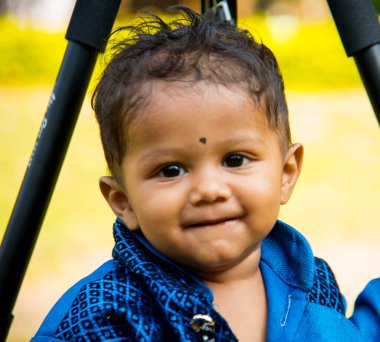 Şirin bir Hintli çocuk bahçede mutlu bir şekilde oynuyor..