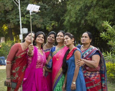 Indian happy women group is taking selfie on smartphone, Smiling together at outdoor. Using selfie stick