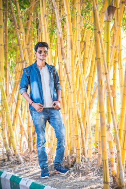 Bambu arka planında yakışıklı, mutlu genç bir adam..