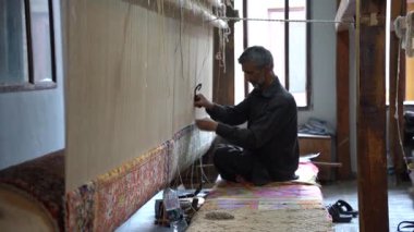 SRINAGAR, INDIA, 28 HAZİRAN 2024 Kashmiri adam elle dokuma makinesi ile bir halı örüyor, Kaşmir halısı dünyada meşhurdur.