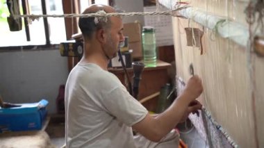 SRINAGAR, INDIA, 28 HAZİRAN 2024 Kashmiri adam elle dokuma makinesi ile bir halı örüyor, Kaşmir halısı dünyada meşhurdur.