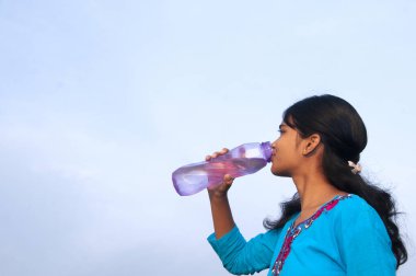 Genç kız açık havada tatlı su içiyor.