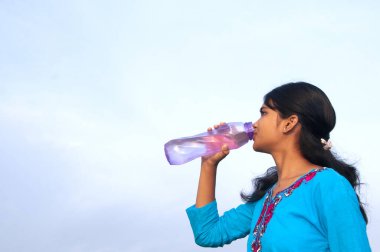 Genç kız açık havada tatlı su içiyor.