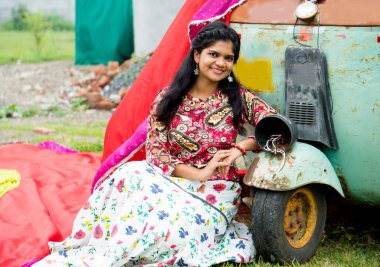 Genç güzel Hintli kız eski aracın önünde.