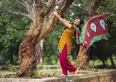 Ağaç gövdesinin yanında genç bir kız ve açık havanın tadını çıkarıyor.