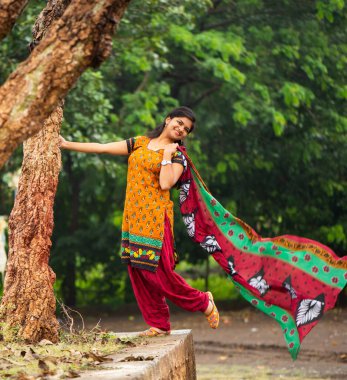 Ağaç gövdesinin yanında genç bir kız ve açık havanın tadını çıkarıyor.