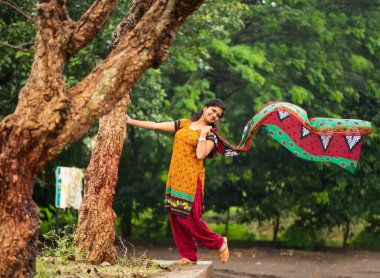 Ağaç gövdesinin yanında genç bir kız ve açık havanın tadını çıkarıyor.