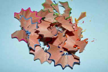 Açık mavi kart üzerinde renkli kalemlerin talaşları.