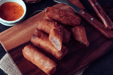 Tahta kesme tahtasına batırılmış soslu kızarmış börek.