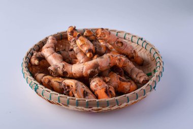 Beyaz arka planda bambu sepetinde taze zerdeçal.