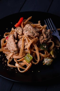 Kızarmış makarna ve siyah tabakta domuz eti.