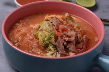 Suki, domuz eti ve sebzeler seramik bardakta, gri arka plan