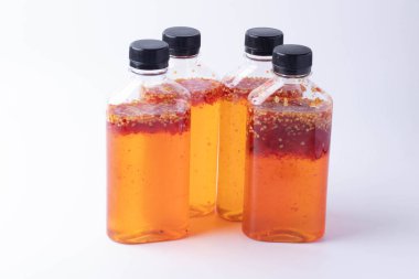 Beyaz arka planda acı biberden yapılmış şişedeki tavuk sosu..