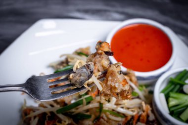 Fasulye filizi ve gevrek un ile kızarmış midye kepçelemek için çatal. Tayland yemeği yakın plan..