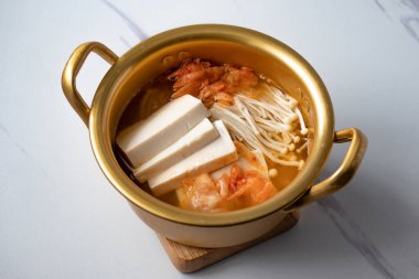 Beyaz arka planda bir kasede tofu ile iğne mantarlı kimchi çorbası, Kore yemeği (Kimchi Jjigae)