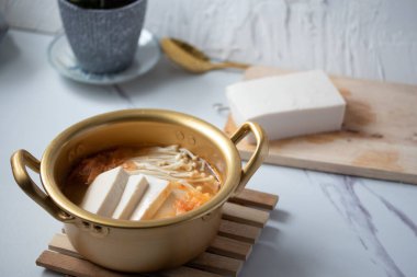 Beyaz arka planda bir kasede tofu ile iğne mantarlı kimchi çorbası, Kore yemeği (Kimchi Jjigae)