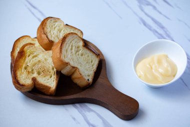 Ahşap tabakta tost ve gri arka planda peynir.