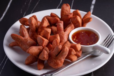 Siyah arka planda baharatlı biber soslu çıtır sosis..