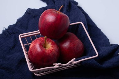 Mavi bir kumaşta üç parlak kırmızı elma.