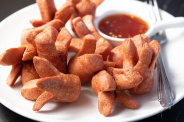 Siyah arka planda baharatlı biber soslu çıtır sosis..