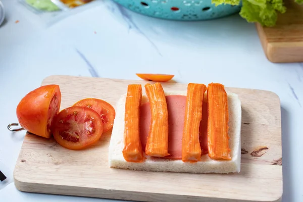 Preparing to make crab stick bread sandwich for breakfast.