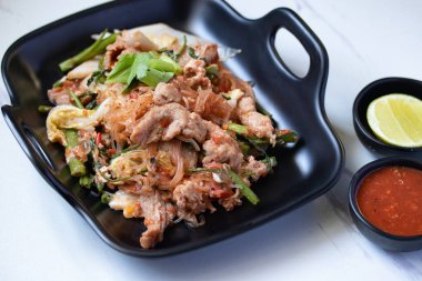 Kurutulmuş sukiyaki ve siyah tabakta domuz eti ve sukiyaki sosu.