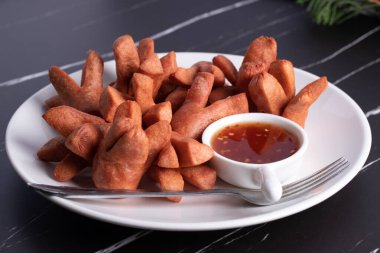 Siyah arka planda baharatlı biber soslu çıtır sosis..