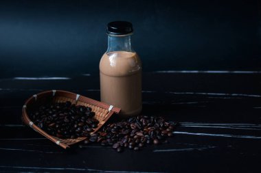 Kahve çekirdekli temiz cam şişelerde kahve iç. Koyu tonlar.