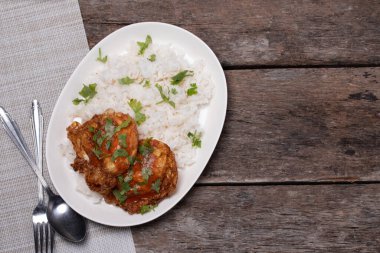 Tahta zeminde beyaz bir tabakta kızarmış yumurta ve pilav..