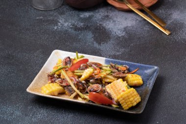 Siyah bir tabakta mısırlı Baharatlı Horoz Salatası