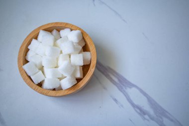 Tahta fincanda gri bir zemin üzerinde granüle şeker küpleri.