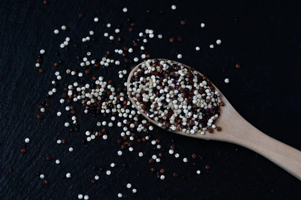 Quinoa Een Houten Lepel Een Zwarte Achtergrond — Stockfoto