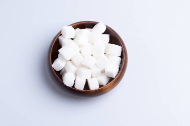 Beyaz arka planda tahta bir fincanda beyaz şeker küpleri