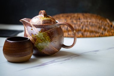 Çaydanlık ve kahverengi bardak Japon seramikleridir, yan yana konmuş çay..