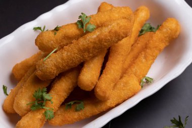 Tavuk nugget çubukları siyah arka planda bir fincanda.