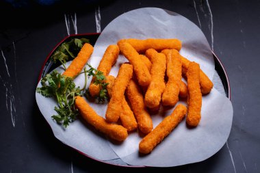 Tavuk nugget çubukları siyah arka planda bir fincanda.