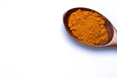 Beyaz arka planda tahta kaşıkta zerdeçal tozu..