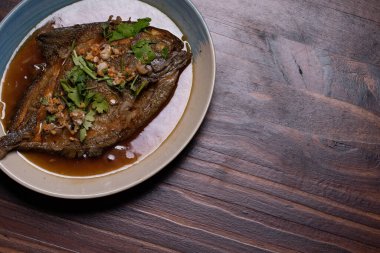 Tatlı soslu kızarmış pomfret. Tahta arka planda Tayland yemeği.
