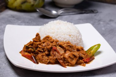 Köri ezmeli kızarmış ton balığı ve beyaz tabakta pilav.