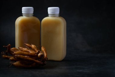 Kaempferia bir şişe ve siyah arka planda taze galingale özütü..