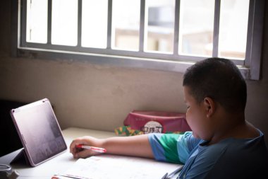 Tayland 'daki koronavirüs durumundan dolayı çocuk evde tabletle çalışıyor..