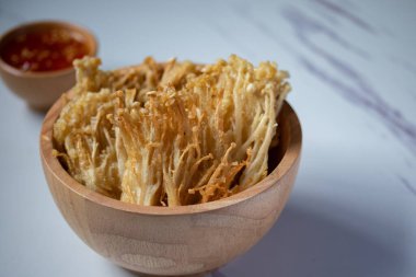 Beyaz tabakta baharat soslu çıtır altın iğneli mantar.