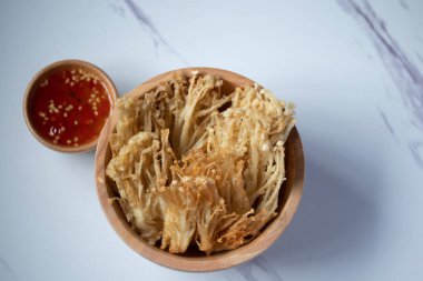 Beyaz tabakta baharat soslu çıtır altın iğneli mantar.