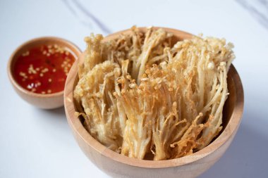 Beyaz tabakta baharat soslu çıtır altın iğneli mantar.