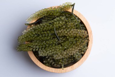 Yosun, beyaz arka planda tahta bir fincanda bir demet üzüm..